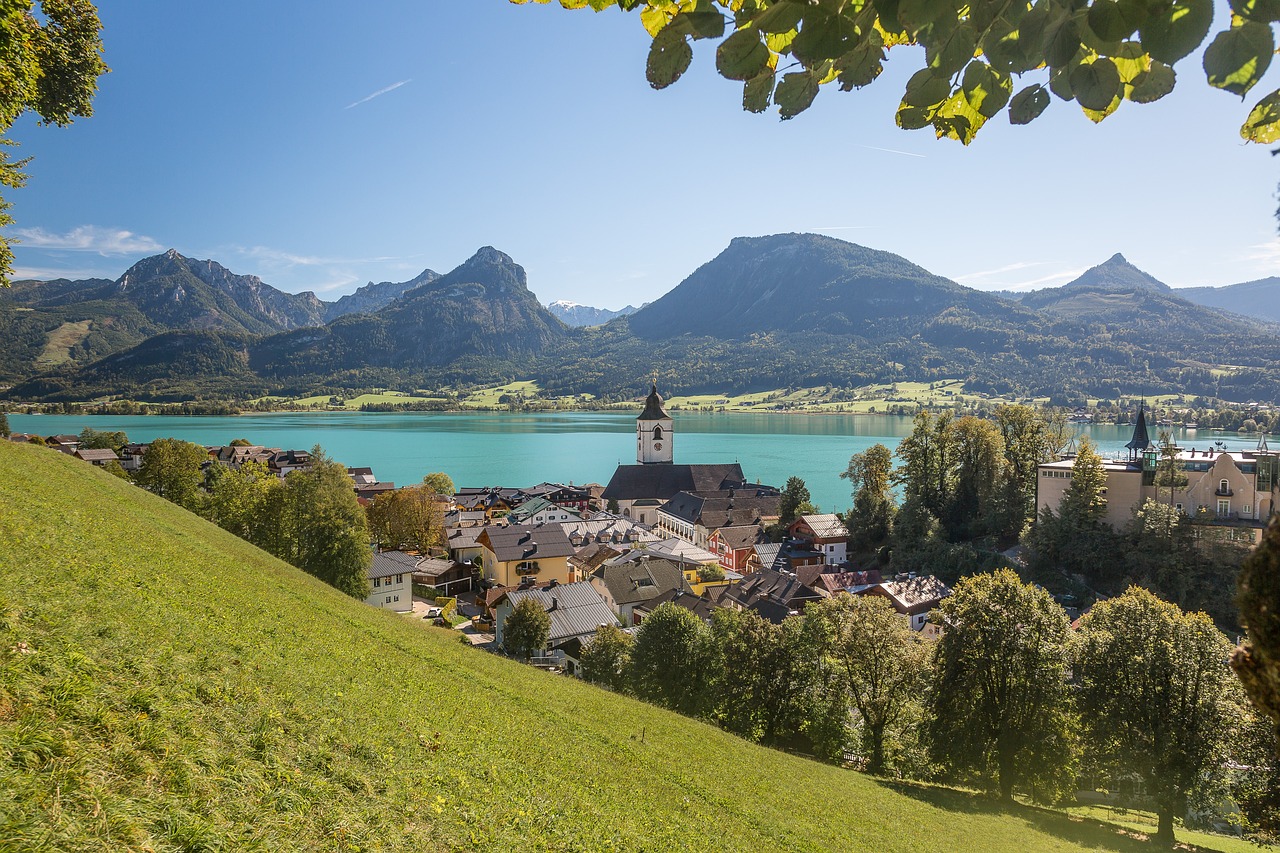 Aerial view of St. Wolfgang in the Salzkammergut region, Austria, showcasing the picturesque town nestled between the glistening Wolfgangsee lake and lush green mountains.