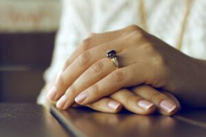 white woman's hand resting on a table with finger nails painted with a French manicure