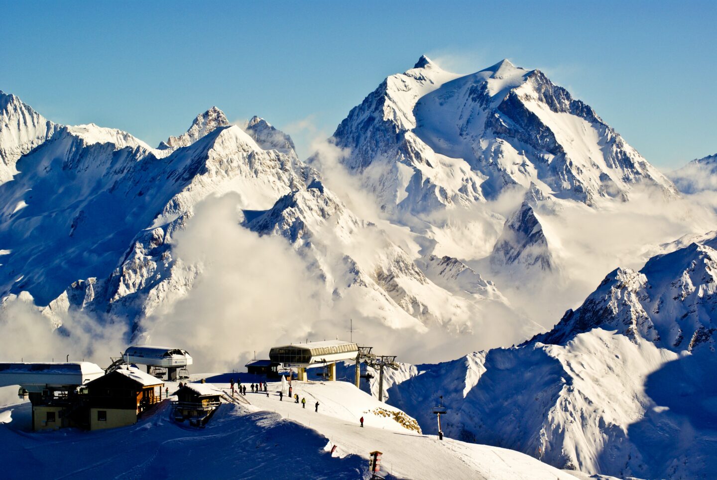 ski europe snow covered mountains blue sky skiers on mountain ski lift