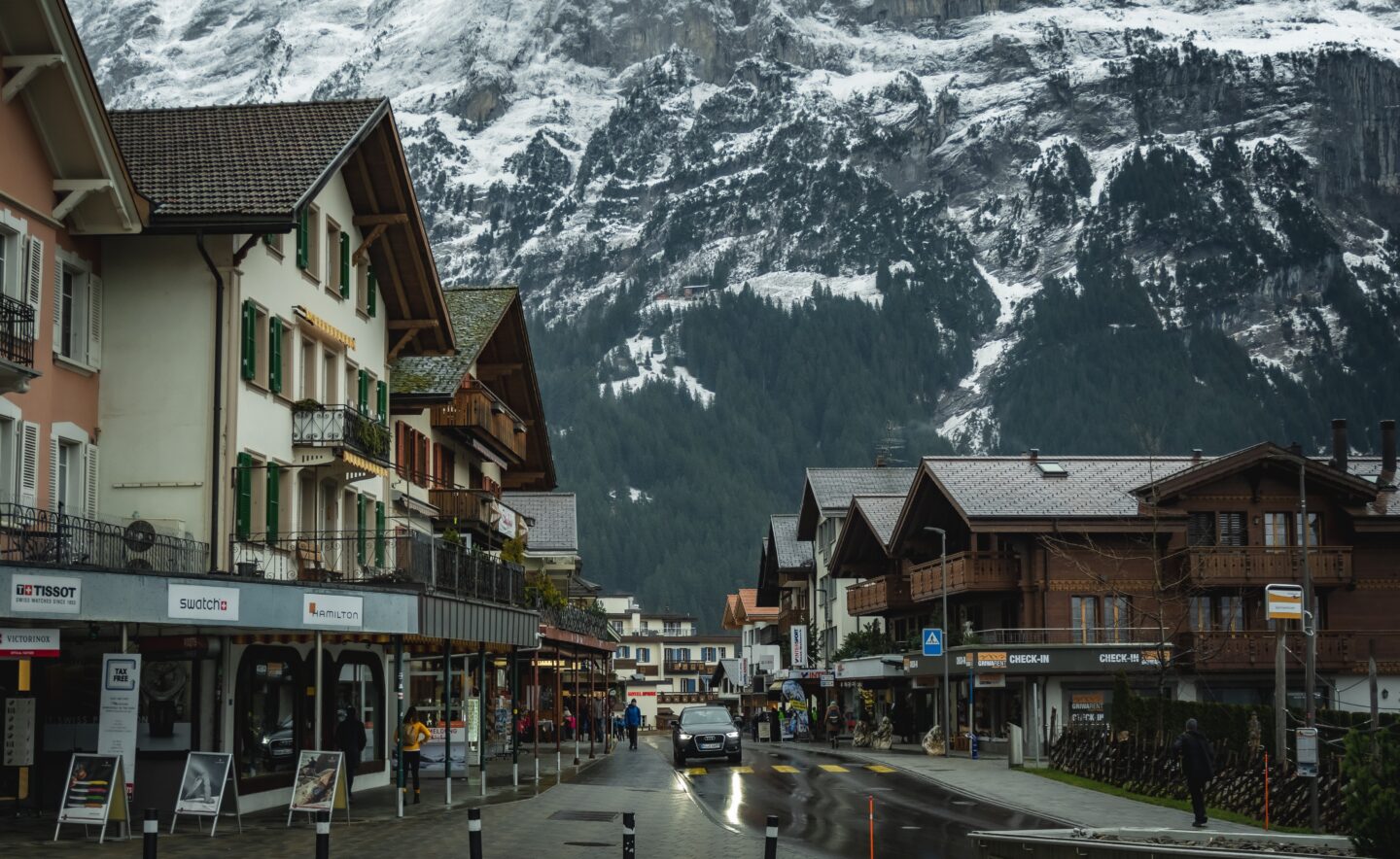 europe street with chalets and snow covered mountains in background