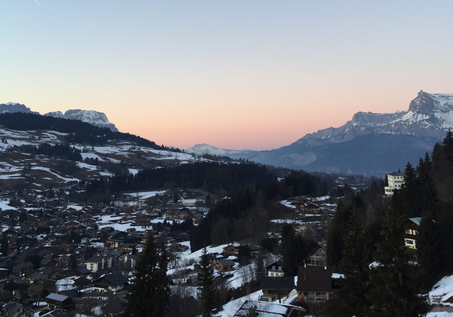 blue sky sunset over mountain town in valley covered in snow with mountains in Megève france