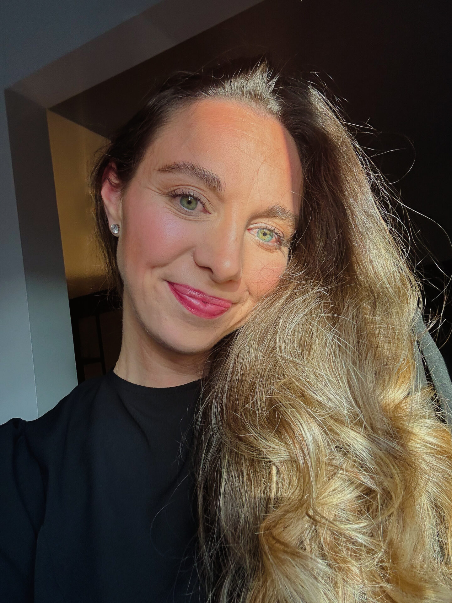 woman smiling in the sun wearing black dress and long blonde hair. Mikaela Higgins